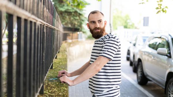 Hipster with beard next to fence