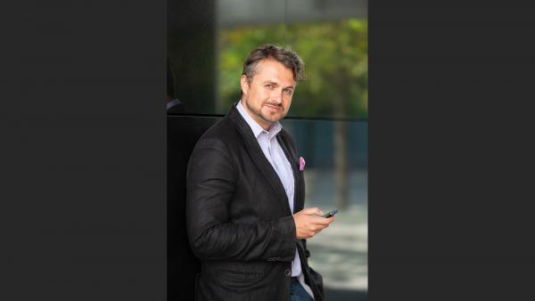 Businessman leans against a mirror wall and holding phone