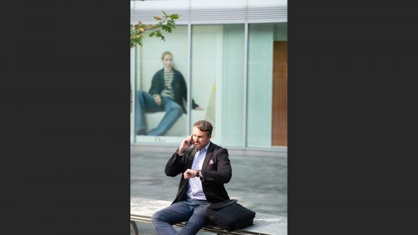Man sitting on the concrete platform and talking on the phone