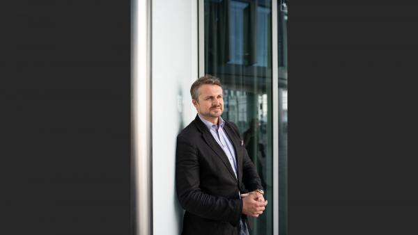 Mature man next to windows and white wall