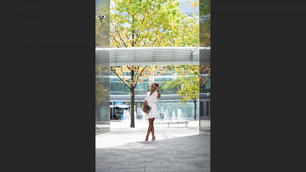 Woman standing on concrete floor next to green tree