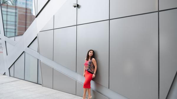 Adult woman on red dress next to modern building