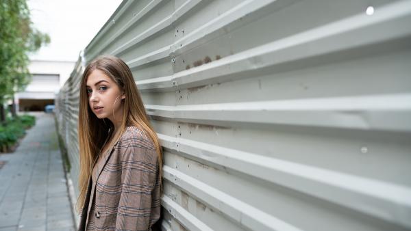 Teenager leans against a sheet metal wall