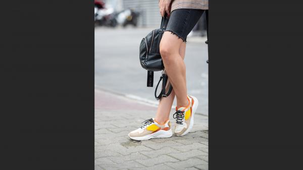 A photo with woman legs, backpack and sneakers