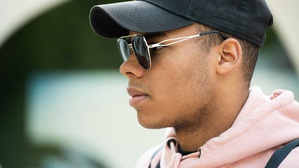 Face of a young man in sunglasses and baseball cap